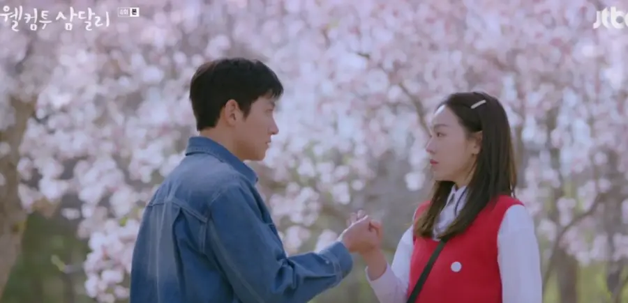 웰컴투삼달리-
벗꽃나무 배경 청자켓을 입은 조용필과 흰블라우스 빨간조끼를 입은 긴머리의 조삼달이 약속하는 장면