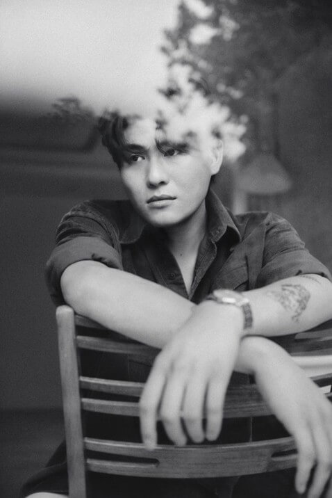 카더가든이-등받이-의장에-거꾸로-앉아-팔을-교차해서-등받이에-걸친-포즈로-오른쪽을-응시하는-흑백-사진