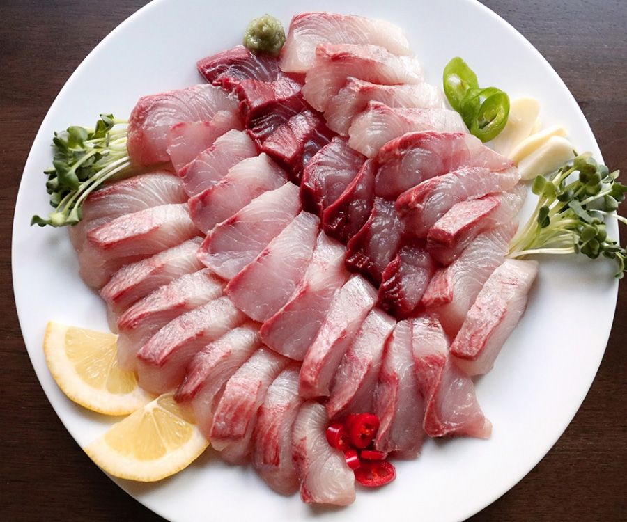 바다에서 채취를 한 방어를 깨끗하게 세척을 한 후에 회를 떠서 동그란 접시에 가지런히 놓아두고 레몬과, 고추, 마늘, 와사비 등을 같이 놓아두고 찍은 사진