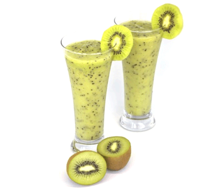 투명 유리컵에 초록색 키위주스가 가득 담겨있고, 유리컵은 2개이다. 컵 주위엔 반으로 잘린 키위들이 있고 컵 위엔 키위 한조각이 걸려있다.