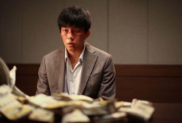 영화 《머니백》에서 피투성이가 된 남자가 거액의 현금 더미 앞에 멍하니 앉아 있는 장면. 돈은 언제나 욕망을 불러오고, 그 끝은 결코 아름답지 않다.