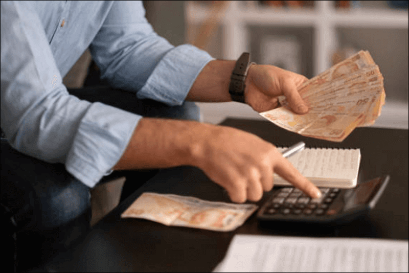 화폐를 세면서 계산기로 계산을 하고 있는 사진