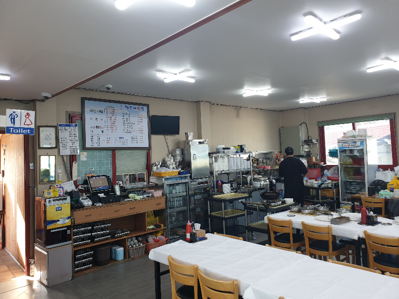 테이블과 의자가 보이는 내부. 직원 한 명이 일을 하고 있다.