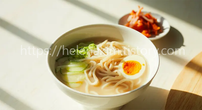 콩국수가 시원하고 맛있게 담겨있고 옆에는 아삭한 김치가 있는 이미지.