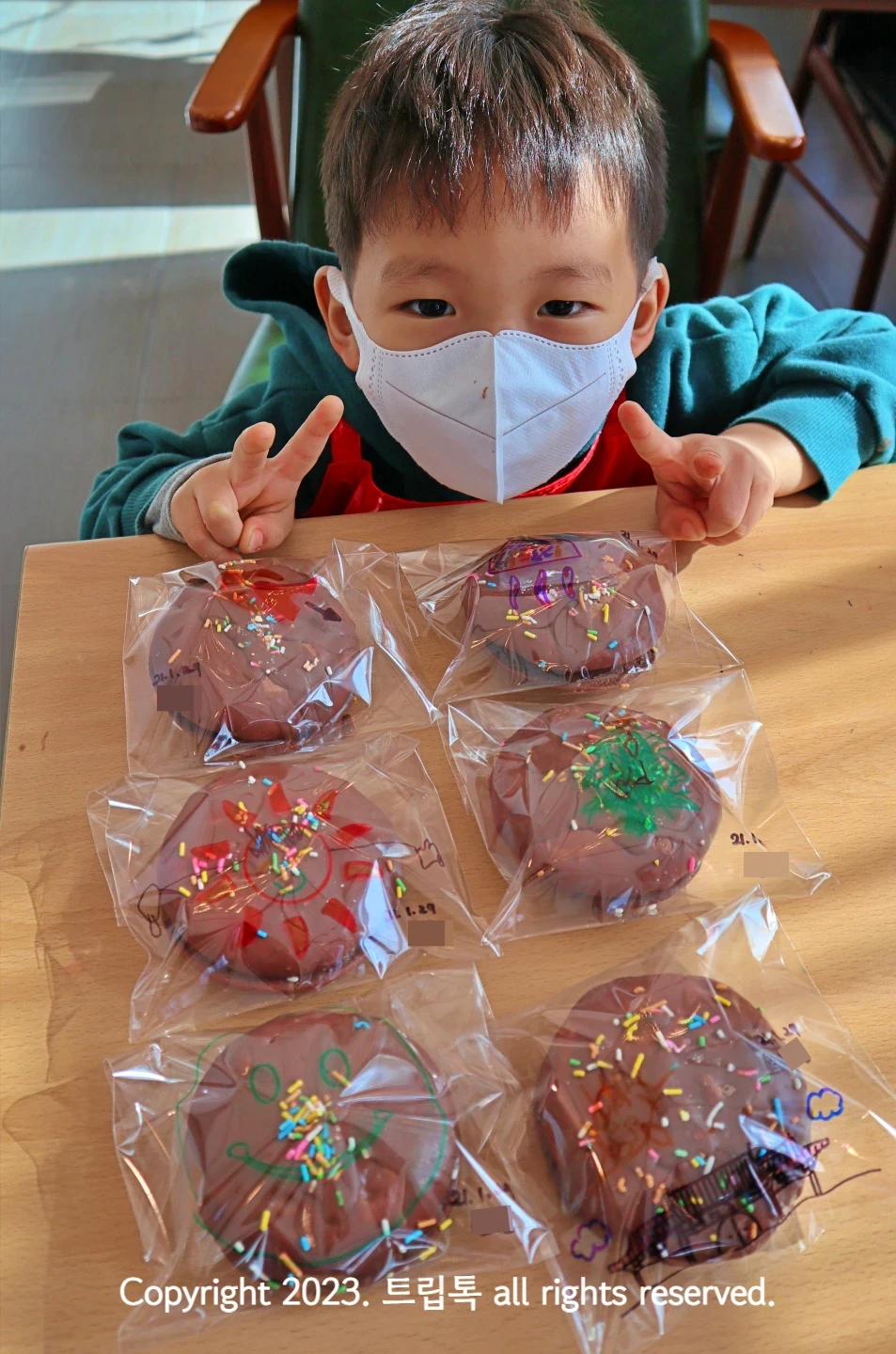 비닐 포장지에 초코파이를 넣고 아이가 v하고 있다.