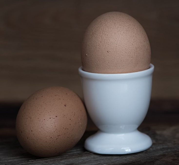 달걀 2개가 놓여있다. 하나는 달걀 컵 안에 들어있다.