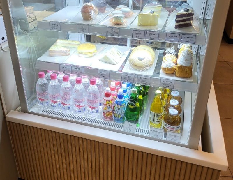 카페 냉장고 쇼케이스 안에 깔끔하게 진열된 어린이용 캐릭터 음료수(뽀로로 음료수) 사진. 초보 사장의 미안함과 진심을 전하며 고객과의 '정서적 유대감'을 형성해 2년 반 단골을 만든 기적의 핵심 도구임.