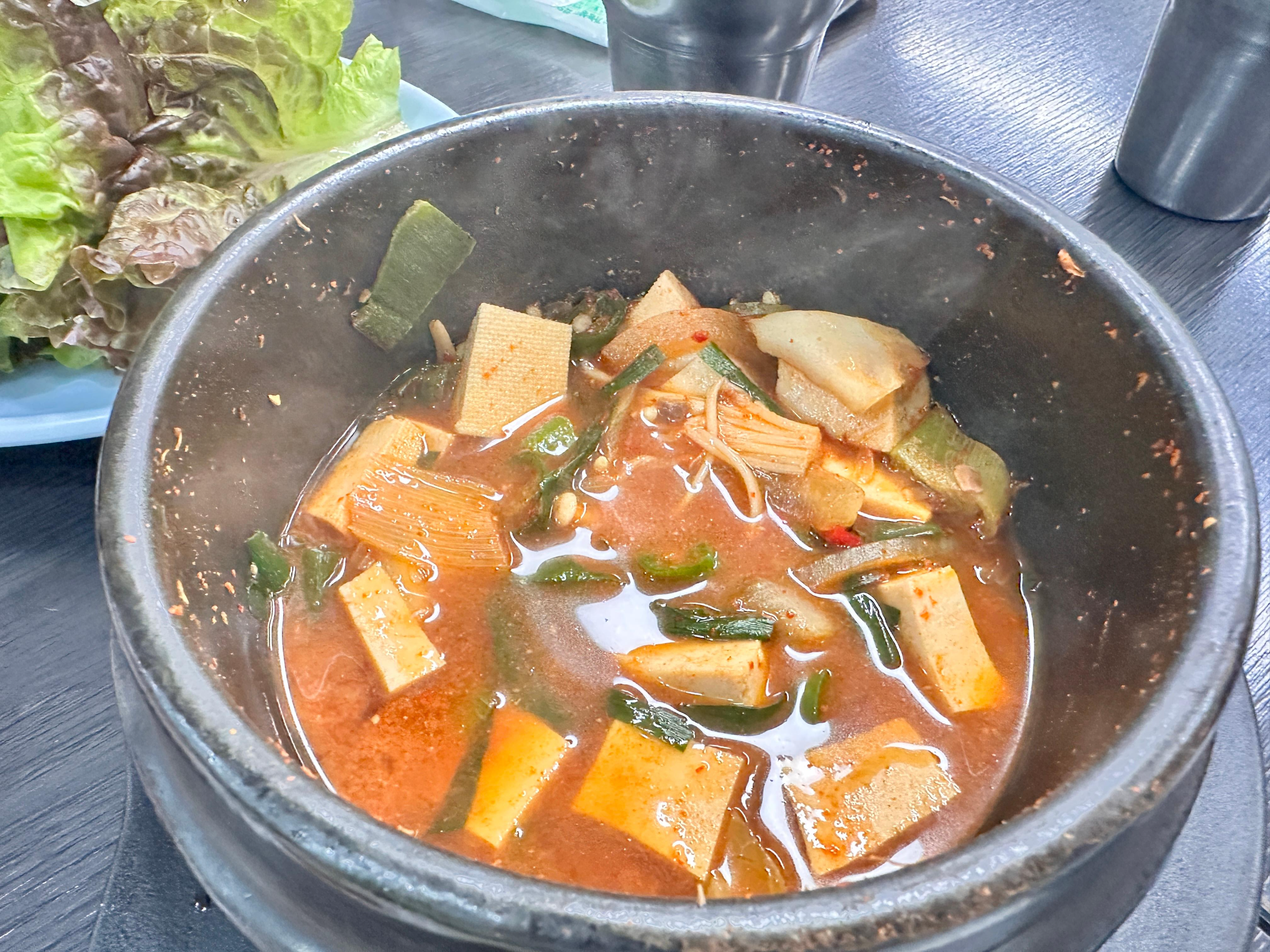 된장찌개 국물과 밥이 섞인 비빔밥이 하얀 공기에 담겨있는 모습. 두부와 채소 조각들이 보임