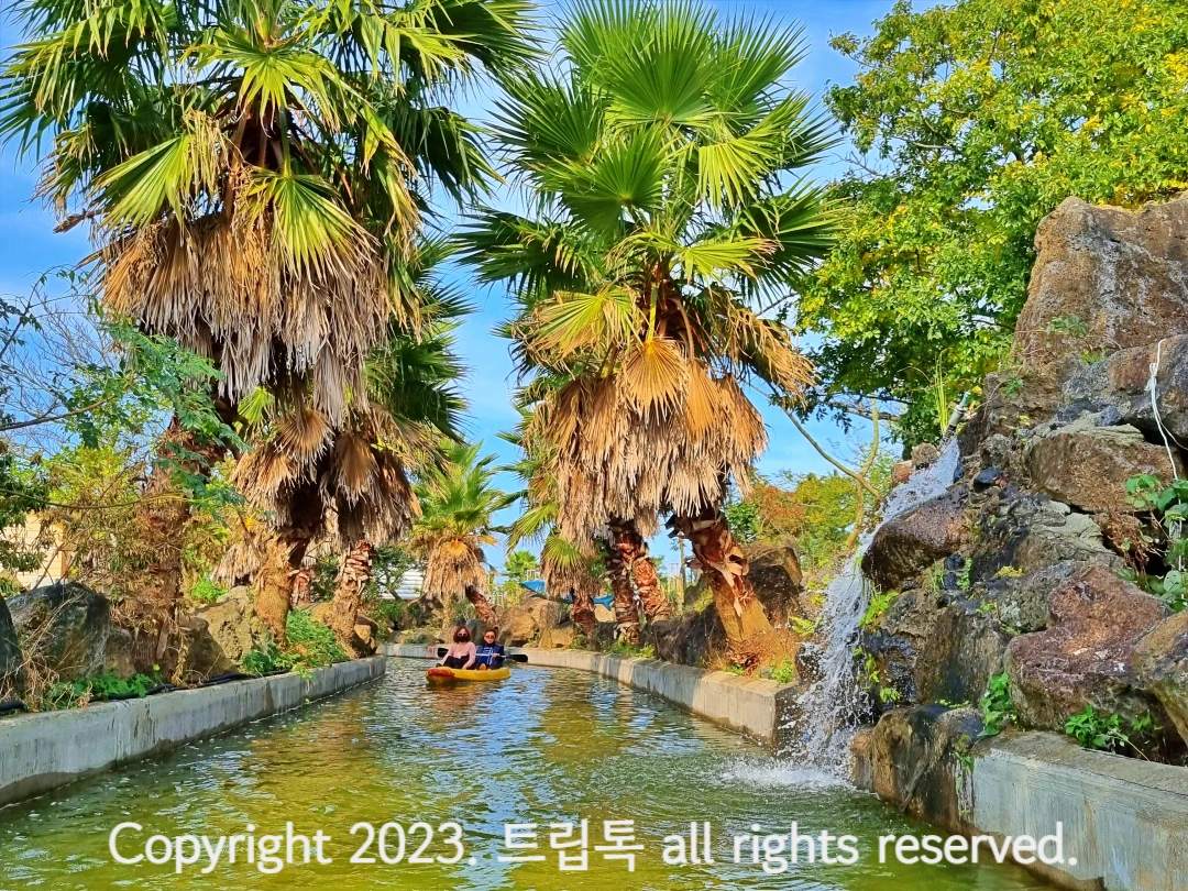 폭포수같이 오른쪽에서 물이 떨어지고 있고 카약을 탄 사람들이 다가온다