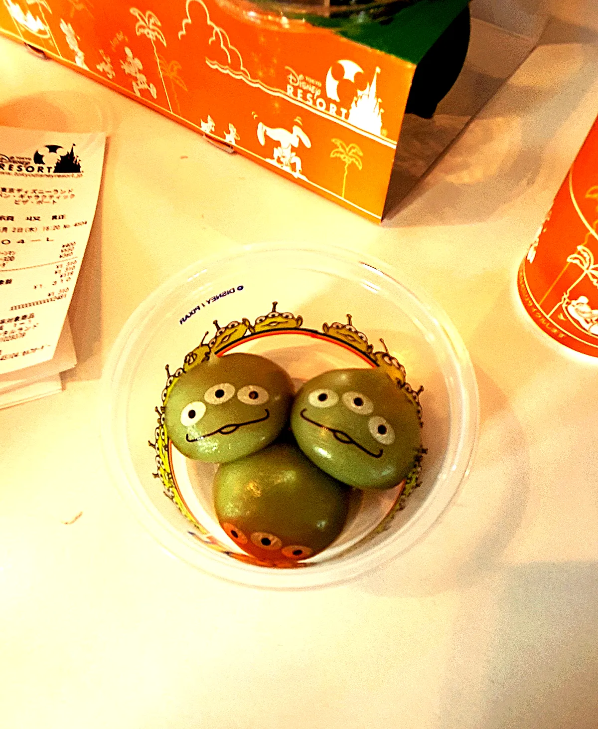 "Green alien mochi held in hand inside Tokyo Disneyland's Tomorrowland area"