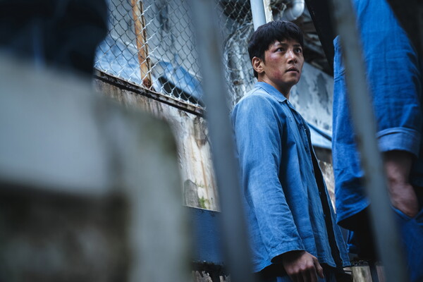 지창욱이 상처 입은 얼굴로 결연한 표정을 지으며 감옥 창살을 통해 어딘가를 응시하는 모습. 억울함과 복수심이 느껴지는 장면입니다.