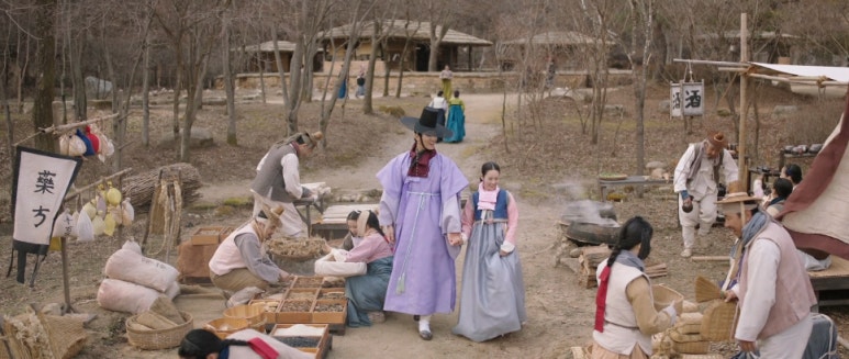 옛 시장 거리에서 남녀가 함께 걸으며 다양한 상점이 있는 장면