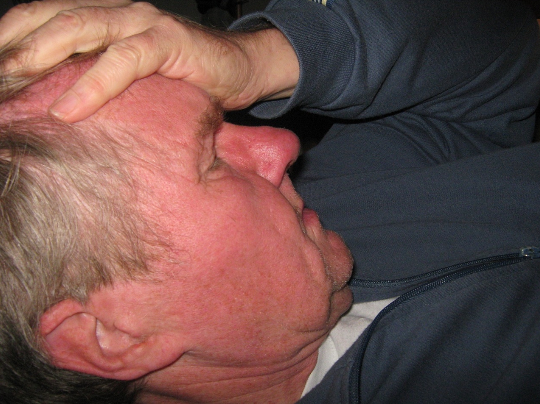 왼손으로 이마를 잡고 누워있는 남성