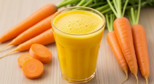 노란빛 당근 주스를 밝은 컵에 담은 모습