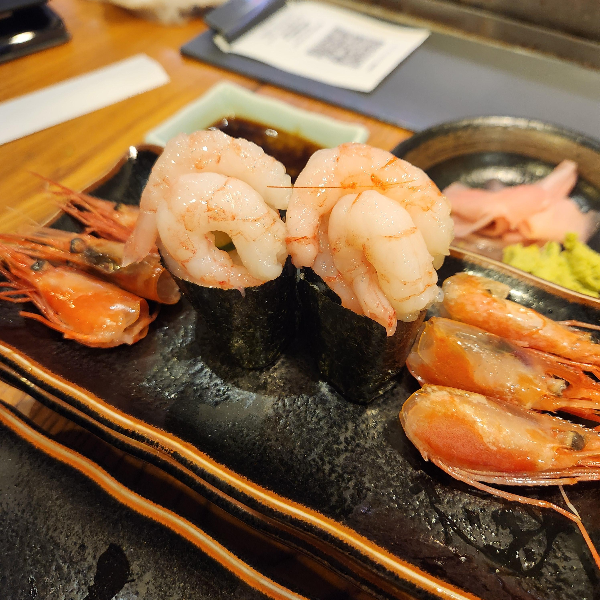 접시위에 새우가 올려져 있다. 세우는 껍질이 벗겨져 있는 몸통과 머리 부분이 나눠져 있다.