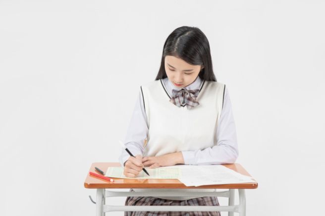 교복을 입고 책상에서 글을 쓰는 여학생