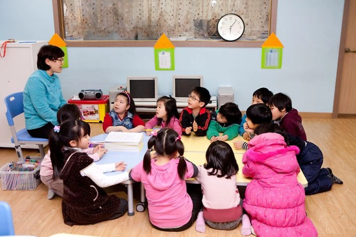 아이돌봄 시설에서 선생님이 아이들을 모아 놓고 이야기하고 있습니다.