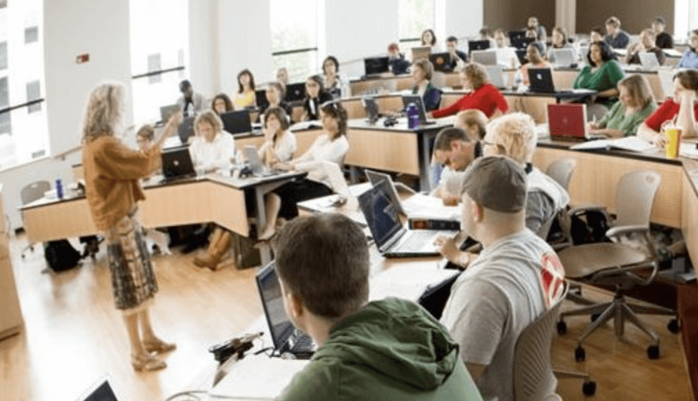 강단에 서서 수업하고 있는 선생님을 바라보는 학생들의 모습
