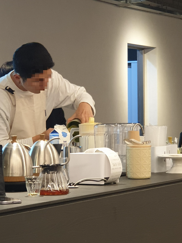 바리스타가 음료를 제조하고 있다. 차선으로 말차를 푸는 중