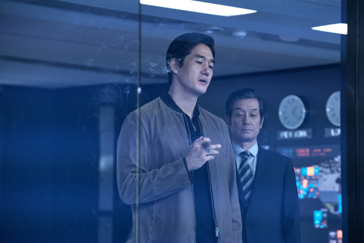 담배피는 남자와 그 남자 뒤에 서 있는 비서