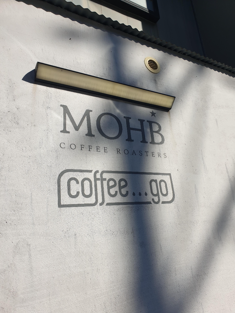회색 벽면에 MOHB Coffee...go라고 쓰여 있다.