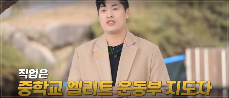 영철이 같은 장소에서 직업에 대해 이야기하는 모습이다. 그는 같은 베이지색 코트를 입고 있으며&amp;#44; 안정적인 자세로 서 있다. 자막: 