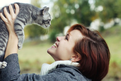 고양이를 안아 올리는 웃는 얼굴의 여성.