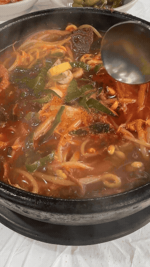 김이 모락모락 나는 해장국을 국자로 휘젓는 장면. 건더기와 국물이 잘 섞이며 더욱 진해지는 순간이 담겨 있다