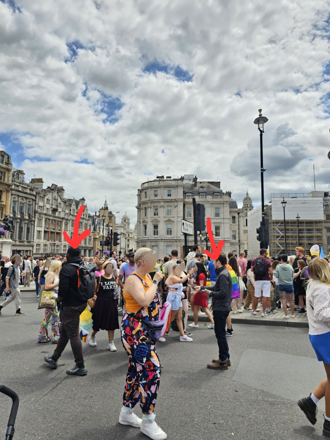 무지개 옷을 입거나 깃발을 든 사람들 사이에 검은 옷을 입은 사람이 둘 보인다. 두 사람의 머리 위에 빨간 화살표로 표시해 두었다.