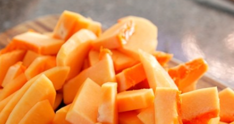 노란 늙은 호박이 작은 조각으로 잘려져 도마위에 올려져 있는 사진