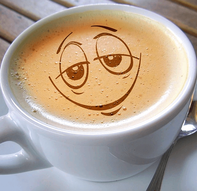 하얀 커피잔에 카페라데가 가득 하다. 위에는 졸린 눈을 한 사람 얼굴이 그려졌다.
