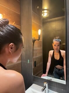 크롭티를-입은-여성이-은은한-조명이-비치는-욕실에서-거울속의-자신을-만족스럽게-바라보는-모습