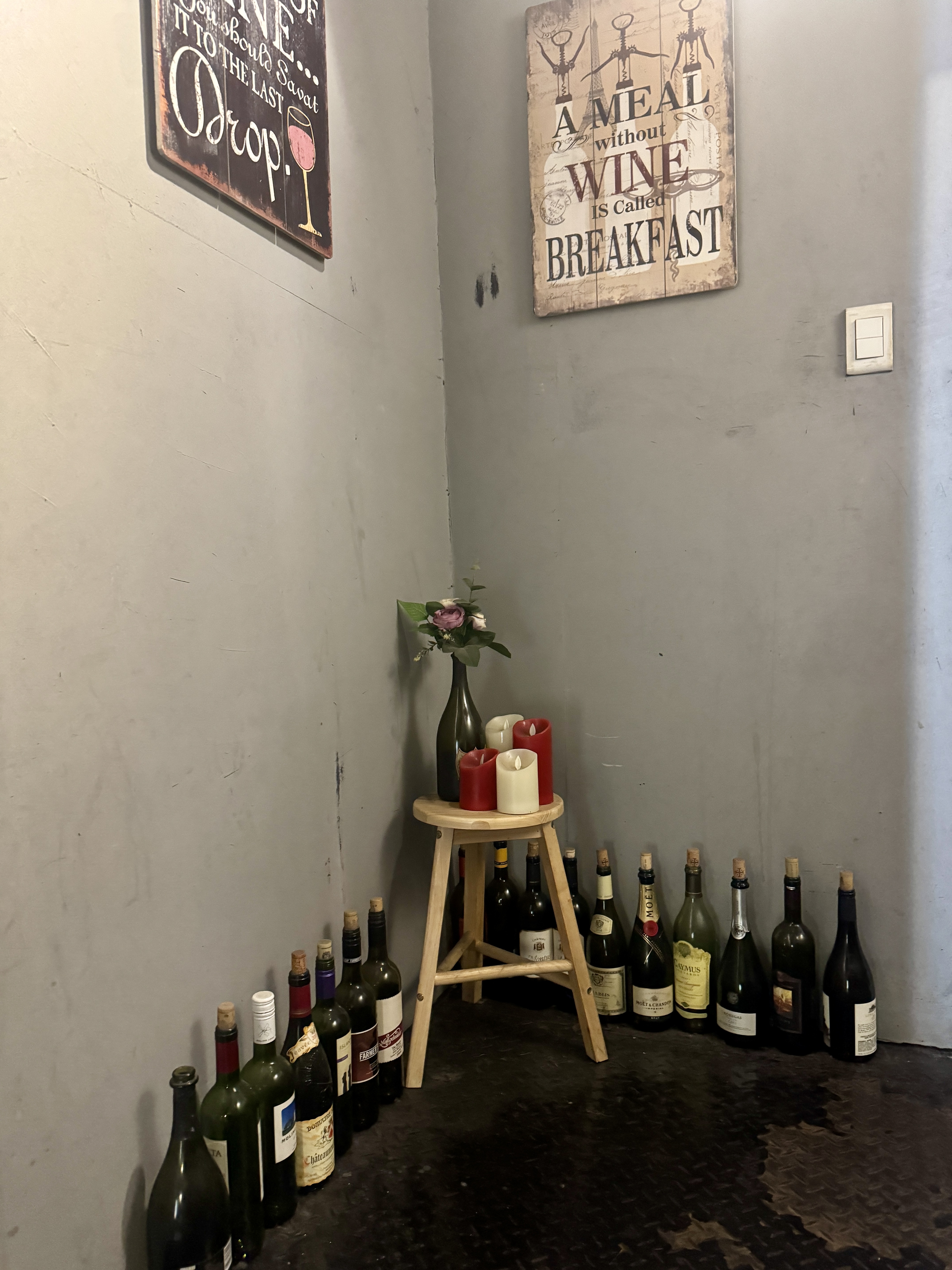 논현 와인바의 벽 한쪽에 빈 와인병들이 장식처럼 놓여 있고&amp;#44; &amp;#39;A meal without wine is called breakfast&amp;#39;라는 문구가 벽에 걸려 있다.