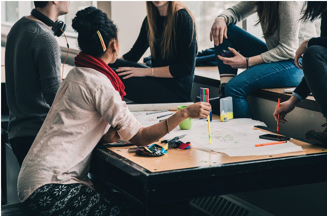 팀원들이 테이블에 둘러앉아 종이에 아이디어를 정리하며 자유롭게 대화하는 모습