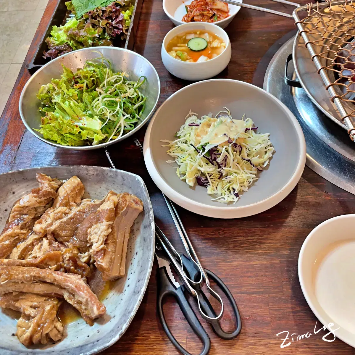 상위에 올려진 밑반찬으로 샐러드, 파겉절이, 채소와 물김치 등이 있음