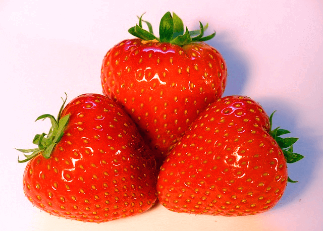 빨간 딸기 3개가 모여있다. 딸기 표면에는 작은 황색의 씨들이 빼곡하다.