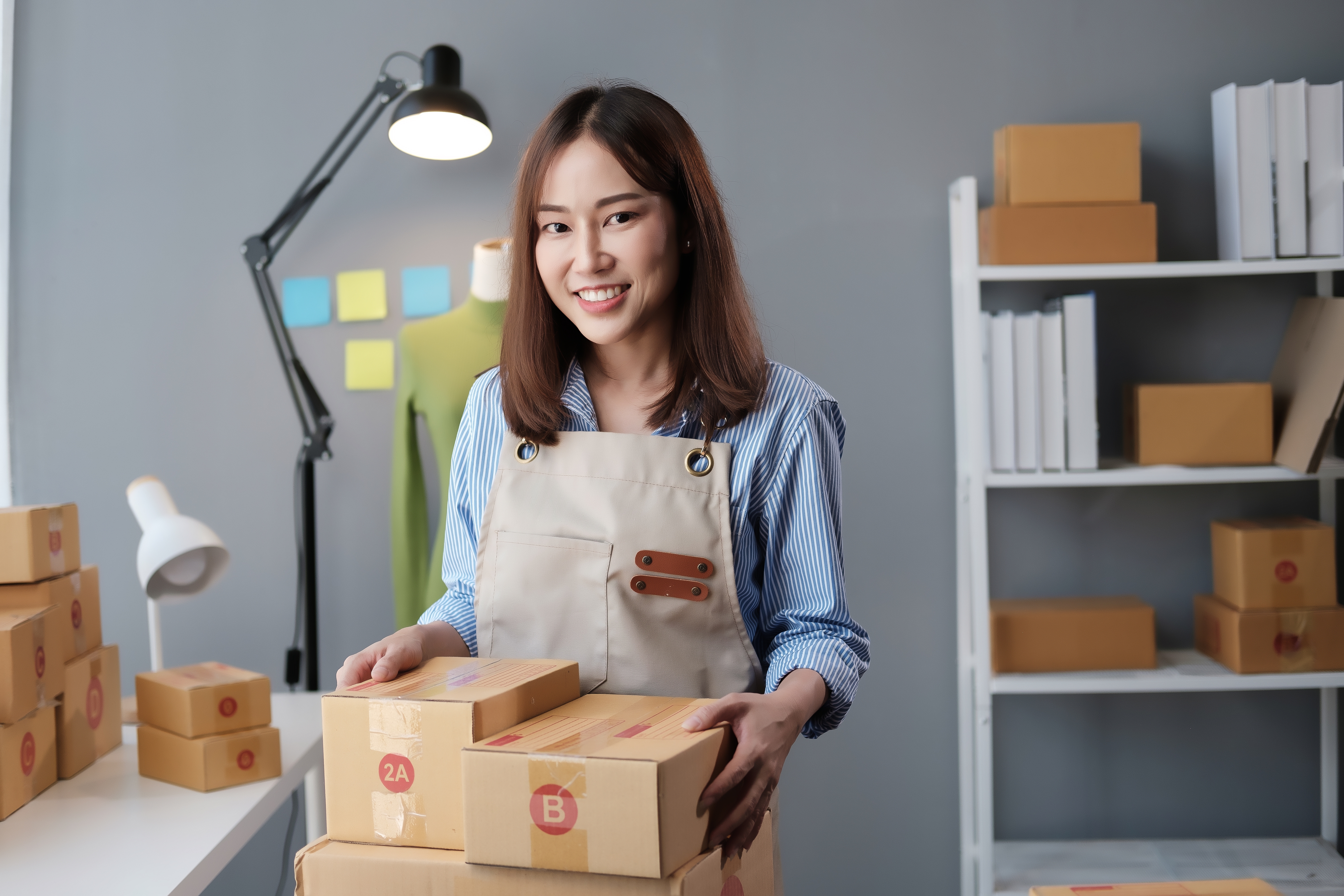 소상공인 여성 창업자가 상품 박스를 정리하며 미소 짓는 모습