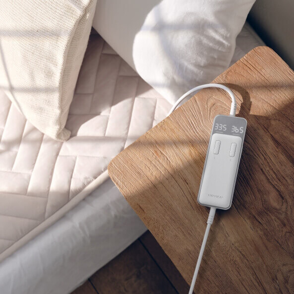 전기매트가 놓인 침대와 옆에 놓인 갈색 테이블