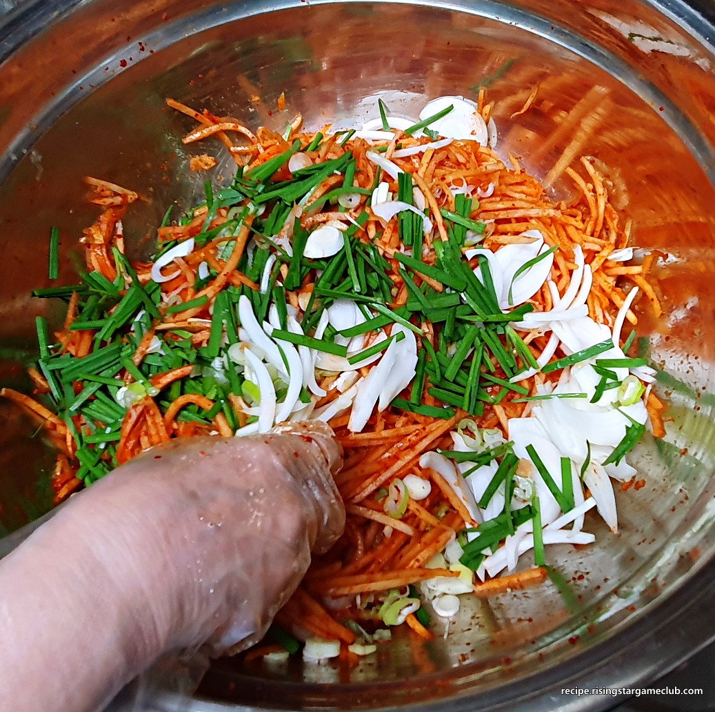 무생채 무침에 준비된 야채(부추&amp;#44; 양파&amp;#44; 파)를 넣어주는 사진