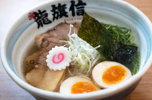 흰색 그릇안에 차슈, 계란 대파등이 국물과 함께 들어가 있다.