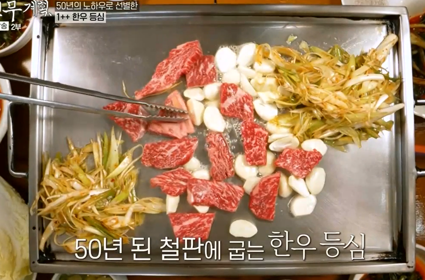 50년된-스테인리스-철판-위에-편마늘과-파채-그리고-참기름과-함께-구워내는-투뿔-한우-등심구이