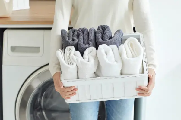 뽀송뽀송한 세탁된 수건을 바구니에 담고 바구니를 들고 있는 남자의 사진