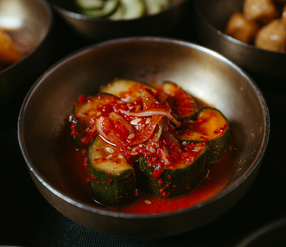 오이를 한 입 크기로 작게 잘라 만든 오이김치. 빨간 고춧가루 와 얇게 채썬 양파 양념으로 버무렸다.