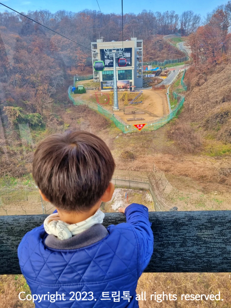 앞으을 보는 아이의 뒷모습과 그앞에 하차할 네모 건물의 전망대가 보인다.