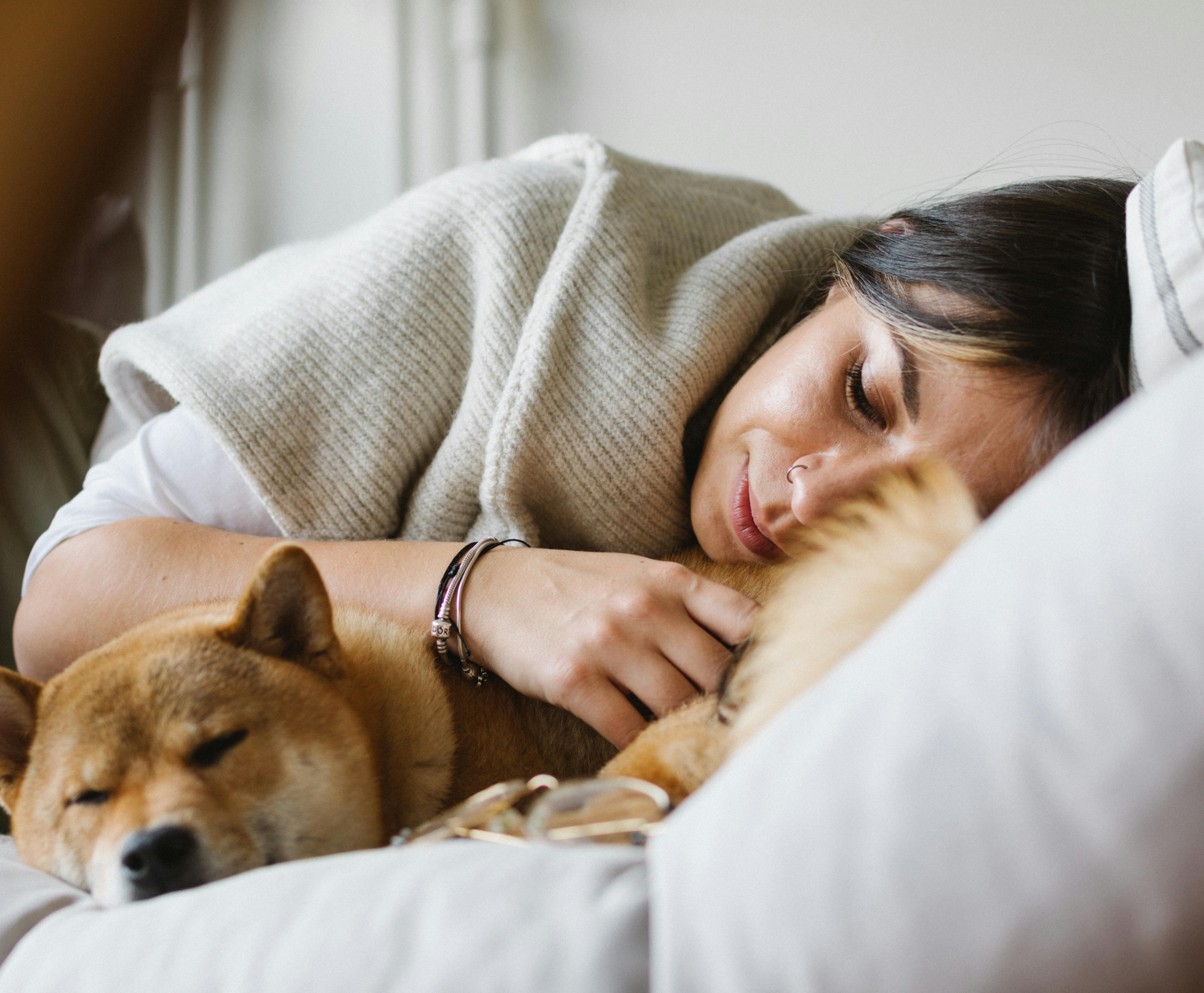 a dog and a woman lying in bed