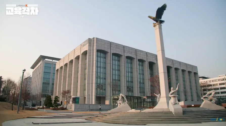 교육 관련 방송에서 독수리 조형물이 세워진 기념탑과 대형 건물의 외관을 보여주는 장면