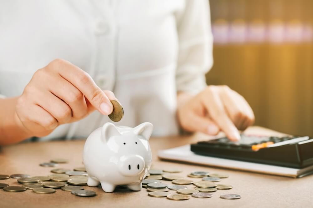 계산기를 누르며 돼지 저금통에 저금하는 모습