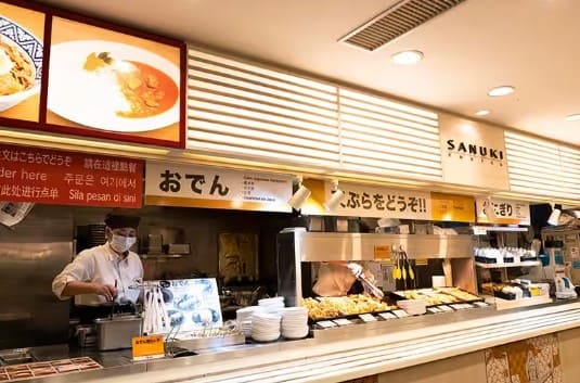 가게 외관 가게 위로 메뉴 사진이 붙어 있고 그 밑에 직원으로 보이는 남성이 있다.