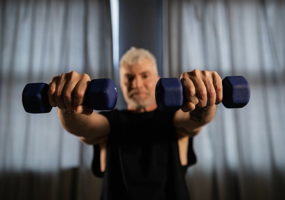 시니어 남성이 양손에 덤벨을 들고 근력 운동을 하는 모습 - via Pexels