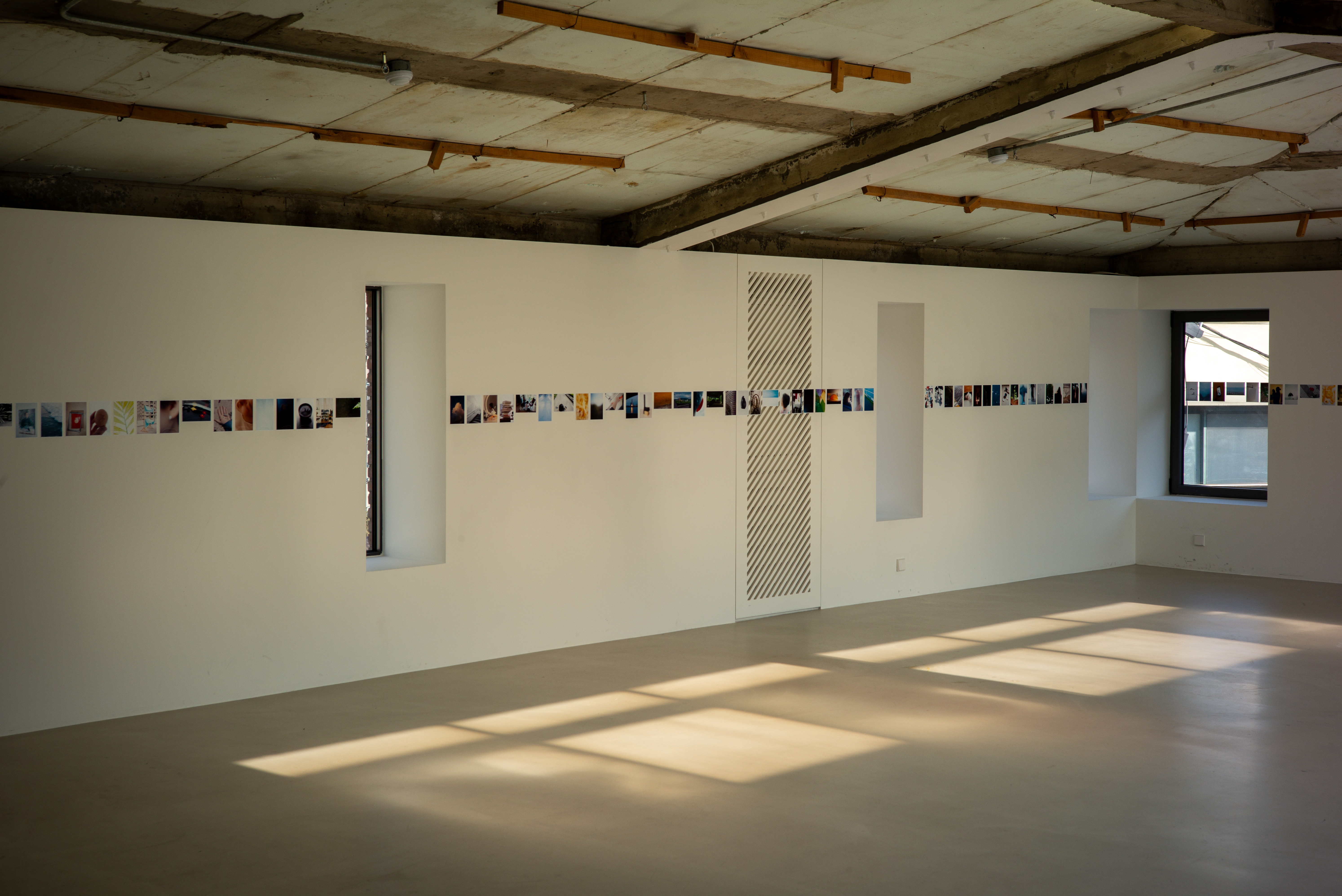 넓은 갤러리 벽면을 가득 채운 사진 작업들과 바닥에 길게 드리워진 오후의 햇살. 라이카 M-P 240 특유의 공간감이 느껴지는 컷.